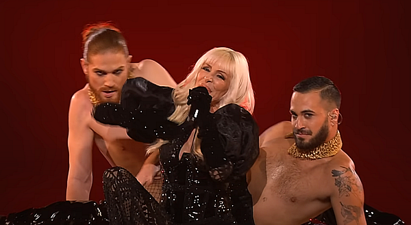 Nebulossa Nebulossa, in black lace, draped by two semi-naked men.